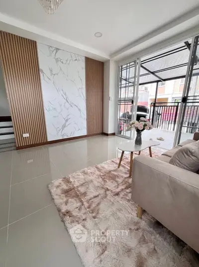 Modern living room with elegant decor and large windows offering natural light.