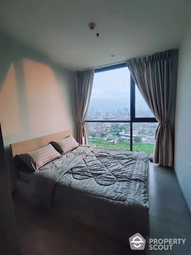 Modern bedroom with large window offering stunning city views and elegant decor.