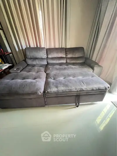 Spacious living room with plush gray sectional sofa and elegant curtains, perfect for relaxation and comfort.