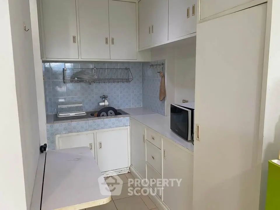 Compact kitchen with white cabinets and microwave, ideal for small apartments.