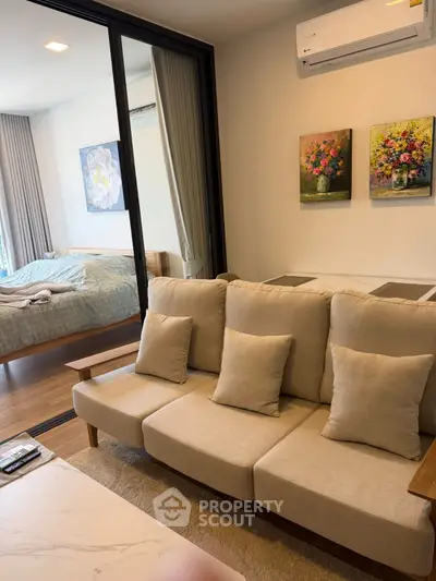 Modern living room with cozy beige sofa and view into stylish bedroom