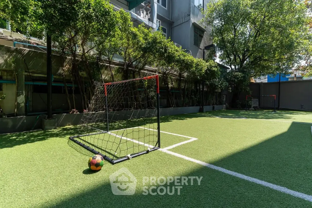Spacious outdoor soccer field with lush greenery in modern residential complex.