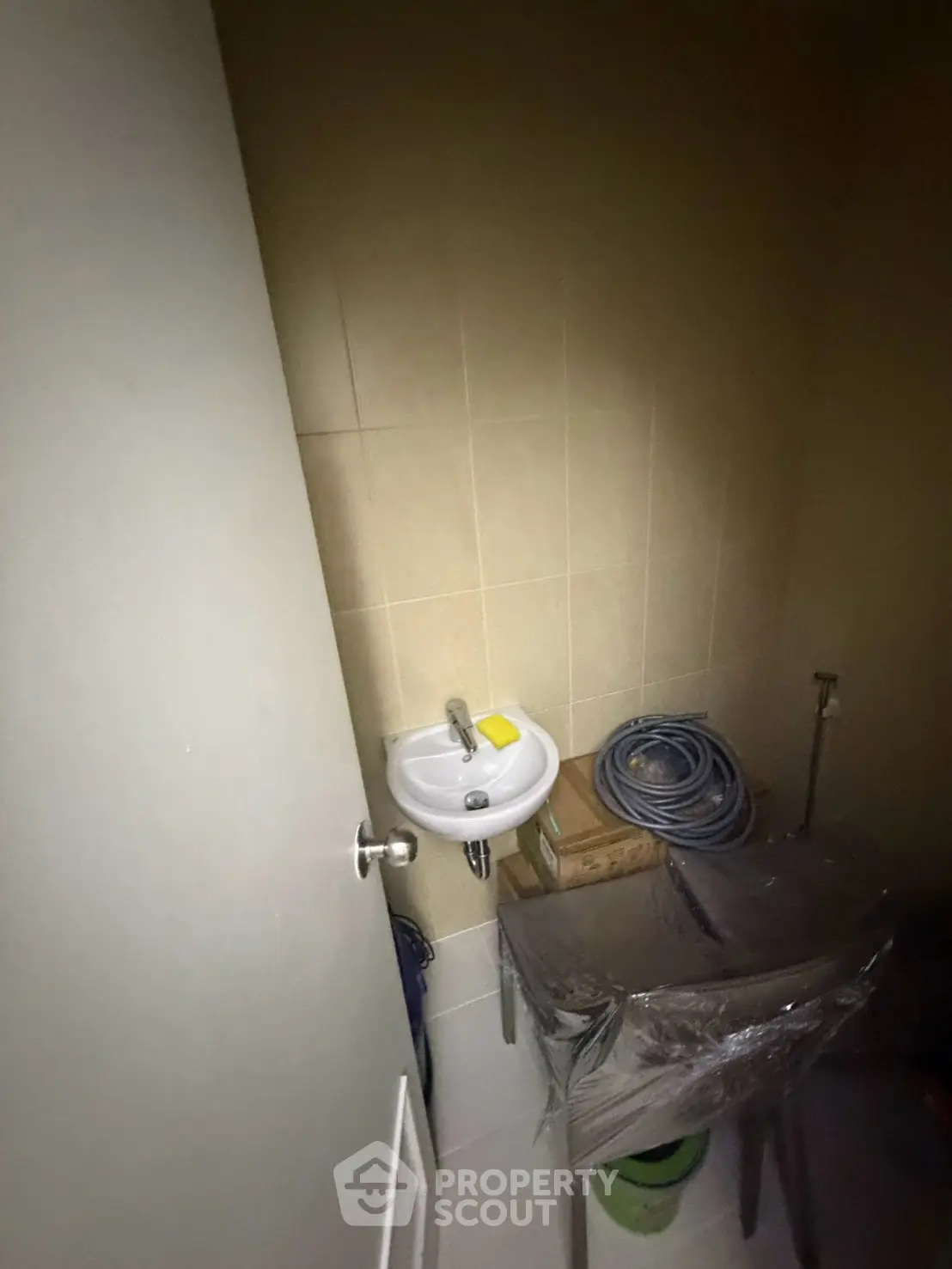 Compact bathroom with small sink and utility storage area