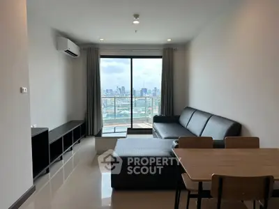 Modern living room with city view, featuring sleek furniture and large windows for natural light.