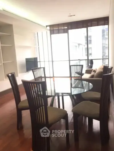 Spacious living room with elegant dining set and large windows for natural light.