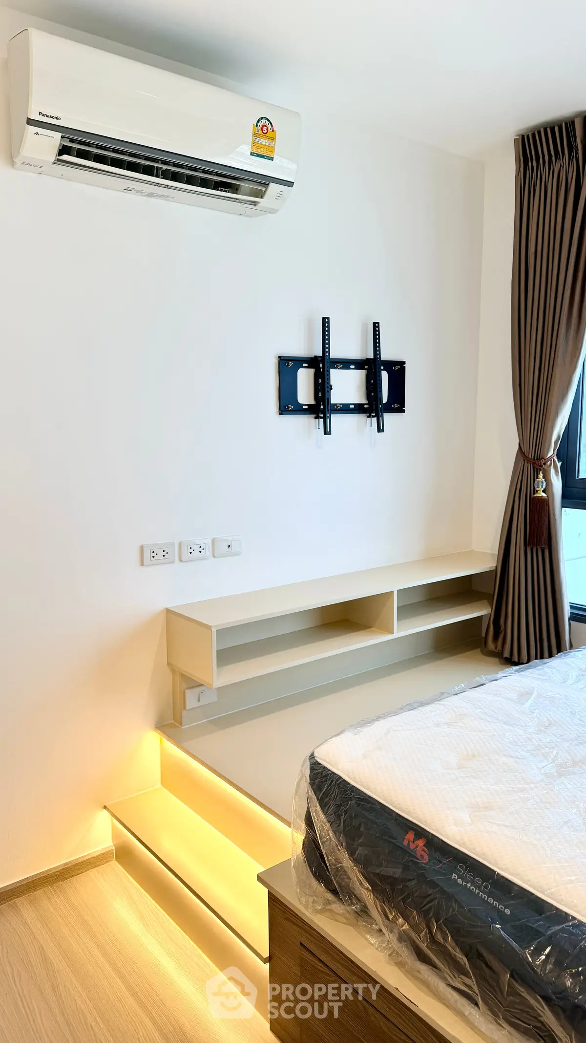 Modern bedroom with air conditioning and mounted TV bracket, featuring sleek shelving and ambient lighting.