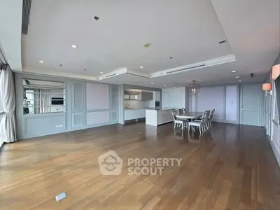 Spacious open-plan living and dining area with elegant wood flooring and modern kitchen.
