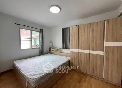 Spacious bedroom with wooden flooring and large wardrobe in modern apartment.