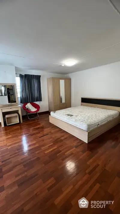 Spacious bedroom with polished hardwood flooring, large bed, and ample natural light, perfect for creating a serene and comfortable personal retreat.