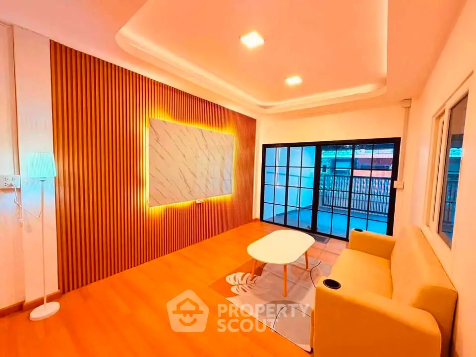 Modern living room with stylish lighting and large windows leading to a balcony.