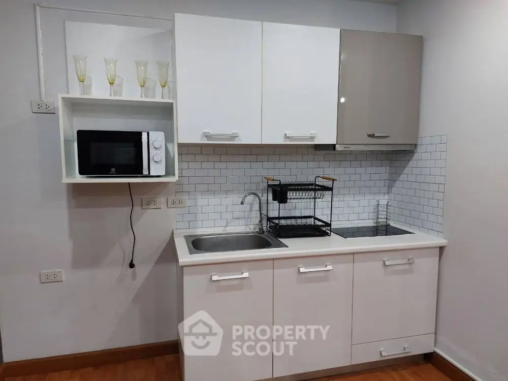 Modern compact kitchen with sleek cabinets and built-in microwave