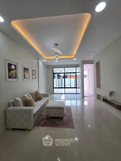 Spacious modern living room with elegant ceiling lights and large windows for natural light.