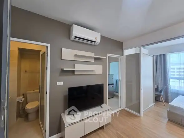 Modern apartment interior with TV, air conditioning, and bedroom view.