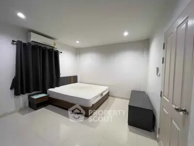 Spacious bedroom with modern furnishings and air conditioning in a minimalist style.