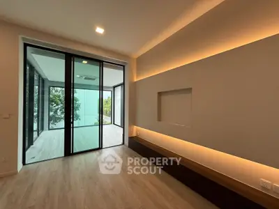 Modern living room with sleek lighting and large glass doors leading to a balcony.