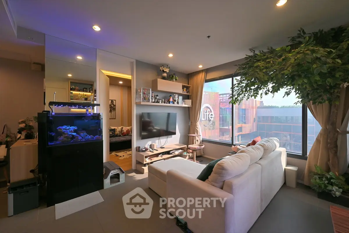 Modern living room with large window and aquarium, offering a cozy and stylish ambiance.
