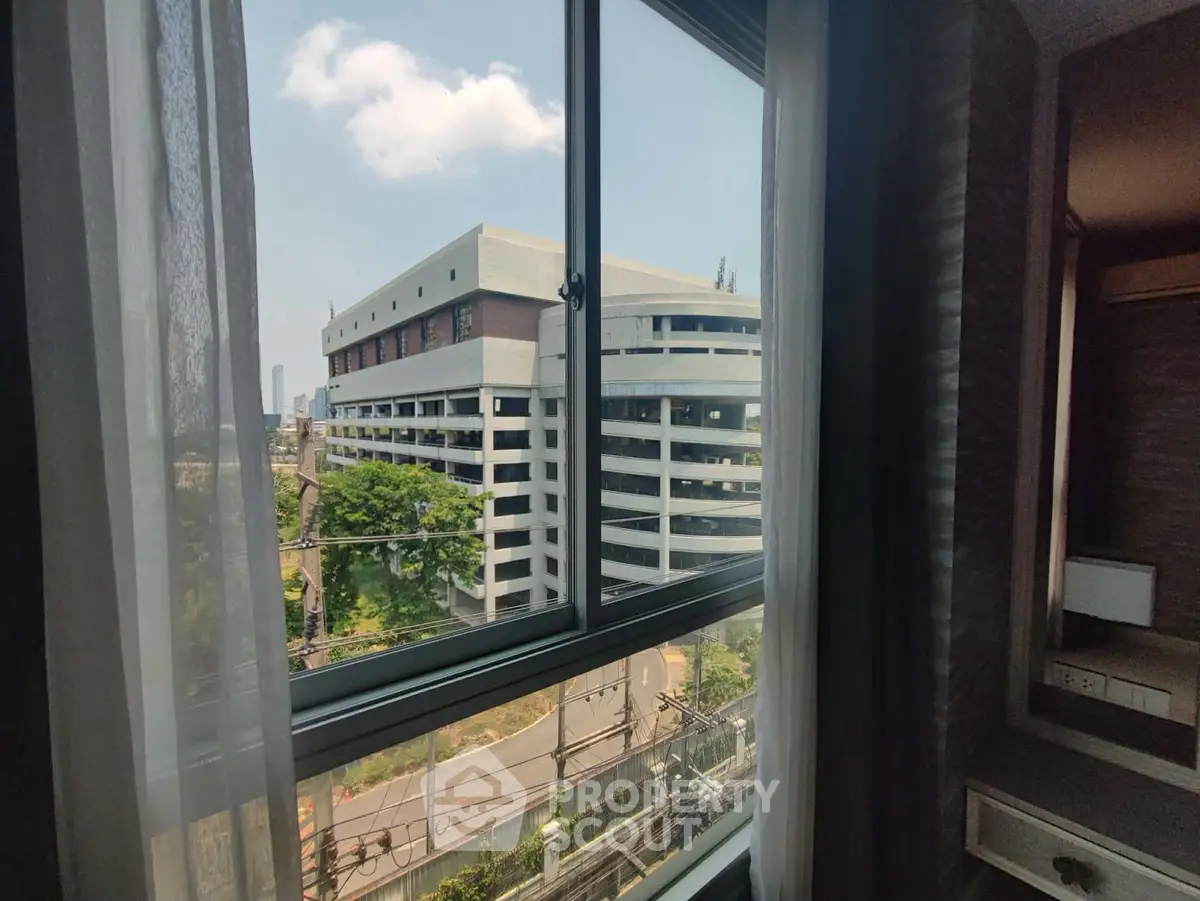 Stunning urban view from a modern apartment window, showcasing cityscape and greenery.