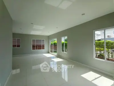 Spacious sunlit living room with large windows and modern tile flooring.