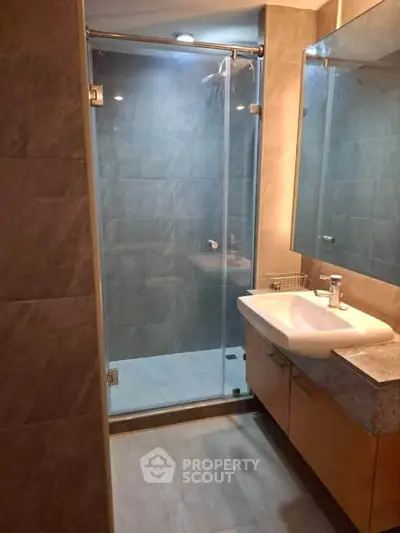 Modern bathroom with glass shower and sleek vanity in contemporary apartment.