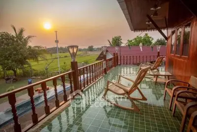 Charming balcony with scenic sunset view over lush greenery, perfect for relaxation.