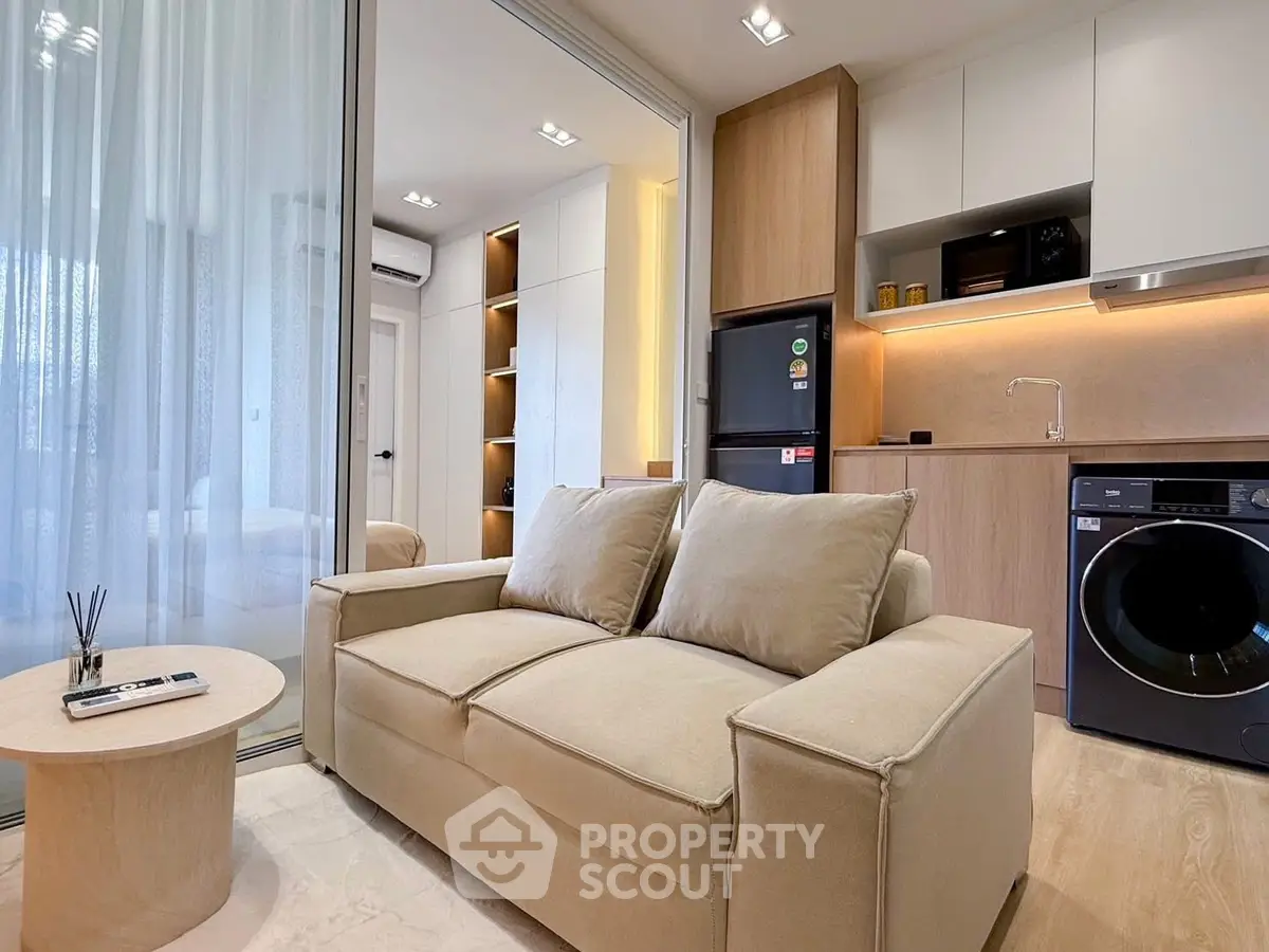 Modern living room with cozy sofa, sleek kitchen, and integrated appliances in a stylish apartment.