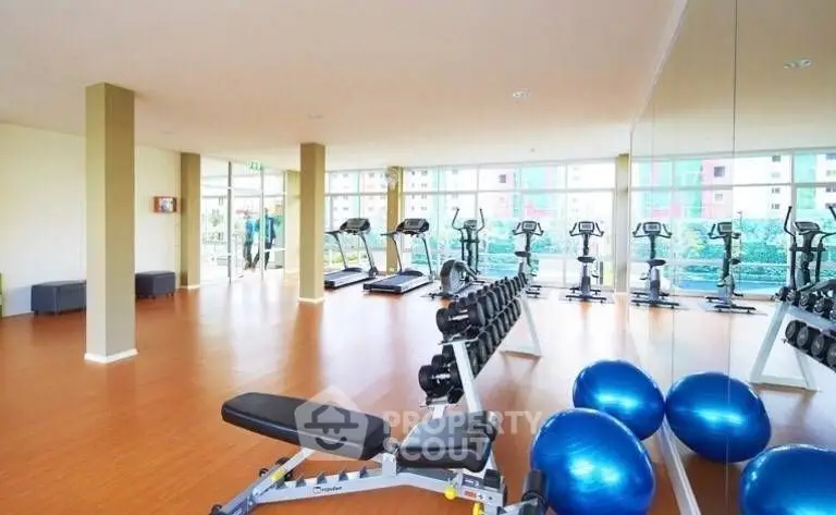 Spacious modern gym with exercise equipment and mirrored walls in a residential building.