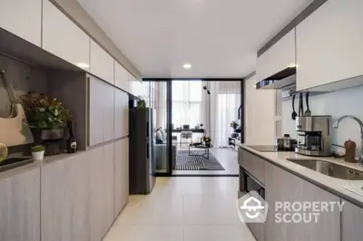 Modern kitchen with sleek cabinetry and open layout leading to dining area.