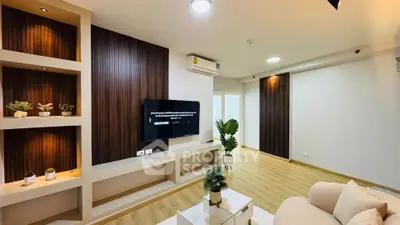 Modern living room with stylish decor and built-in shelving, featuring a wall-mounted TV and air conditioning.