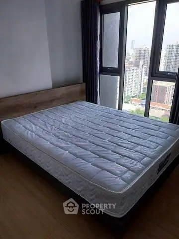 Spacious bedroom with large window offering city view and natural light.