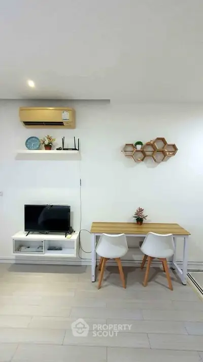 Modern living room with minimalist decor, featuring a TV, air conditioning, and stylish furniture.
