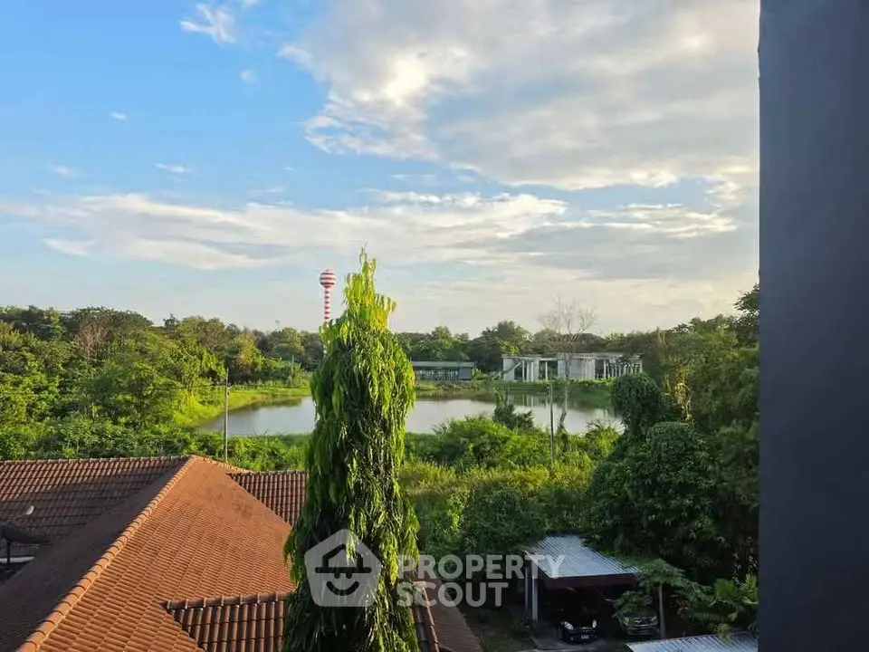 Scenic view from a property overlooking lush greenery and a serene pond, perfect for nature lovers.