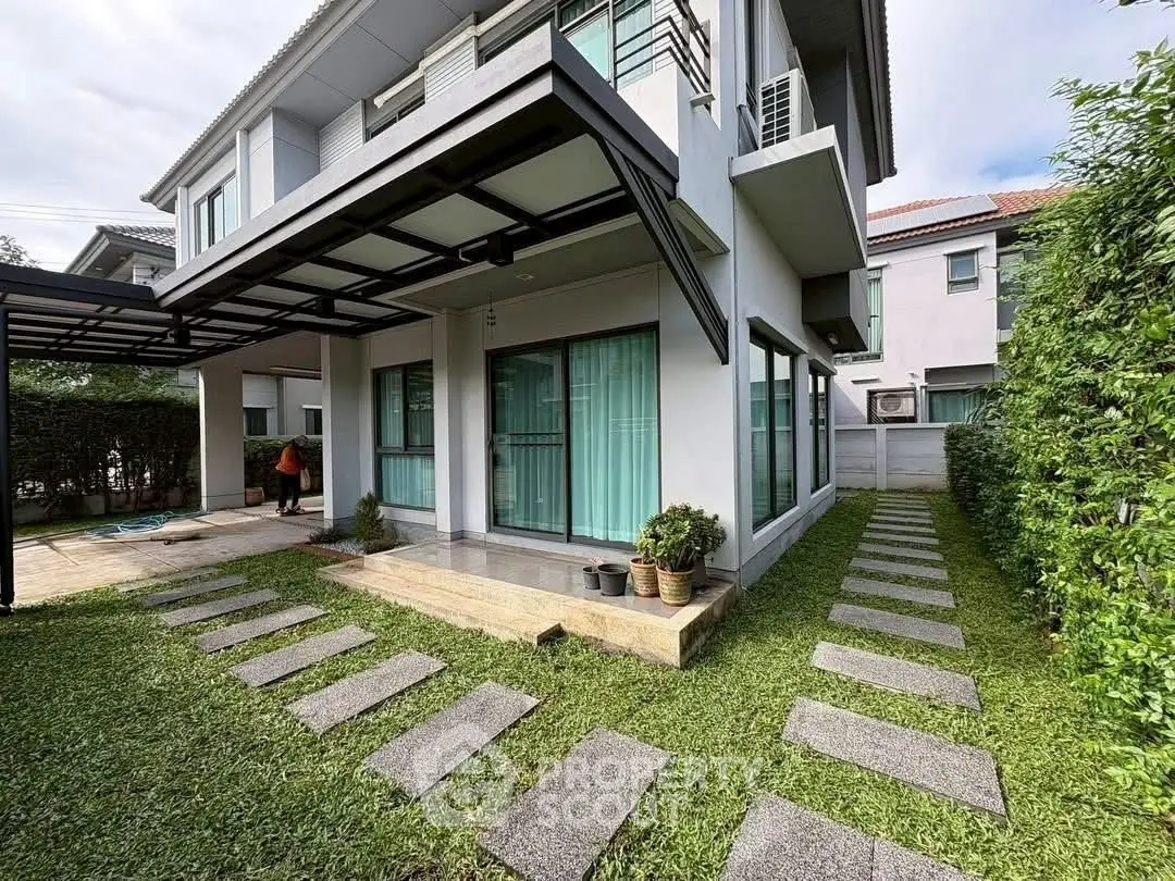 Modern two-story house with landscaped garden and pathway, featuring large windows and stylish exterior design.