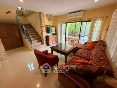 Spacious living room with stylish furniture and natural light, featuring a cozy sofa and elegant staircase.