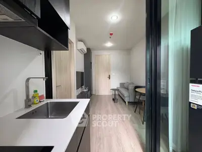 Modern apartment interior with sleek kitchen and cozy living area, featuring contemporary design and natural light.
