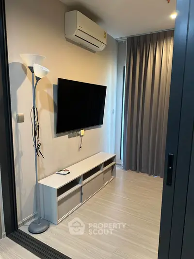 Modern living room with wall-mounted TV and air conditioning in stylish apartment.