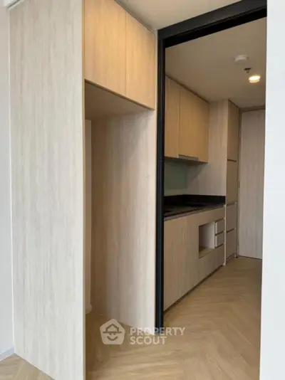 Modern compact kitchen with sleek wooden cabinetry and black countertops
