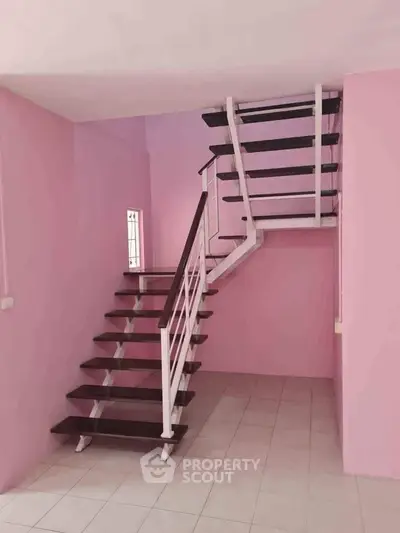 Charming pink interior staircase with modern design and sleek wooden steps.