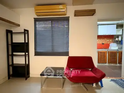 Cozy living room with modern red chair, black blinds, and air conditioning unit.