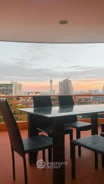 Stunning balcony view with modern dining set and city skyline at sunset.