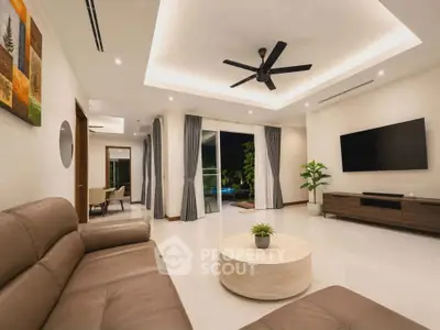 Spacious modern living room with elegant decor and open layout, featuring a large TV and stylish furniture.