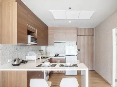 Modern kitchen with sleek wooden cabinets and white countertops, featuring built-in appliances and stylish decor.