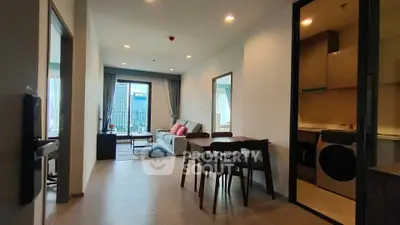 Modern apartment interior with open living room and kitchen, featuring stylish furniture and city view.