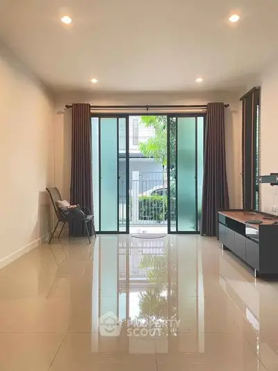Spacious living room with glossy tiled floors and large sliding glass doors leading to a balcony.