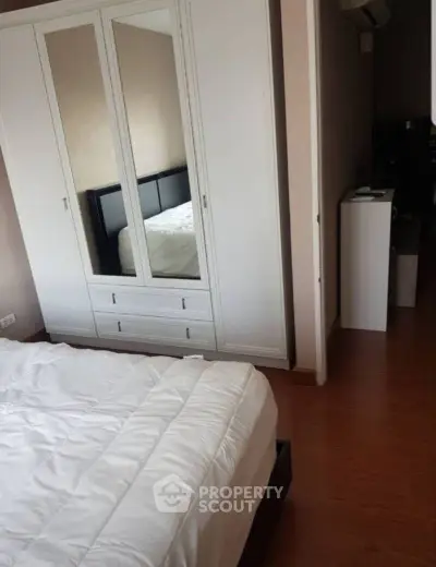Cozy bedroom with mirrored wardrobe and wooden flooring in modern apartment.