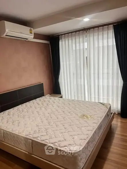 Cozy bedroom with large window and air conditioning, perfect for relaxation.