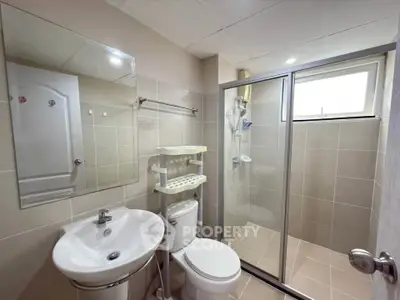 Modern bathroom with glass shower, sleek sink, and neutral tiles.