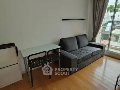 Cozy living room with modern sofa and dining table, featuring large window for natural light.