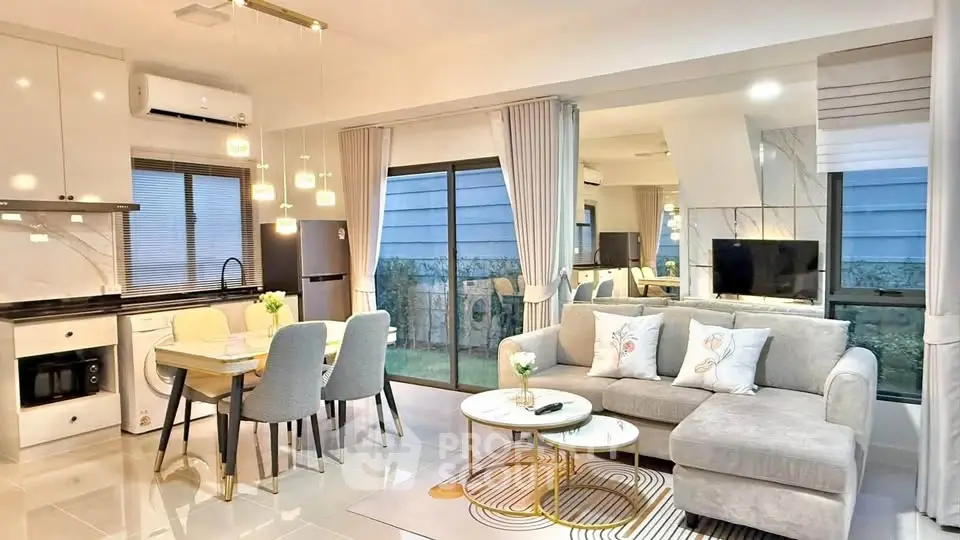 Modern open-plan living room and kitchen with elegant decor and ample natural light.
