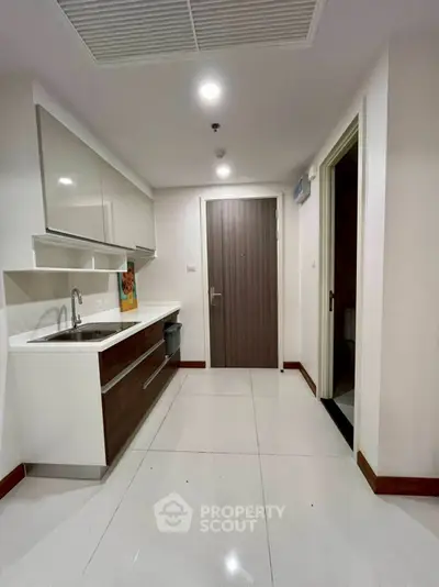 Modern kitchen with sleek cabinetry and white tile flooring in a contemporary apartment.