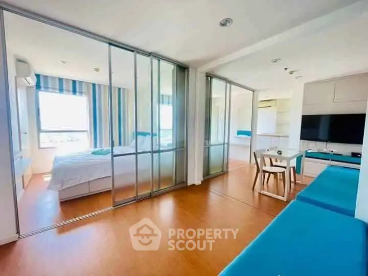 Modern apartment with open layout, featuring a cozy living area and a stylish bedroom separated by glass doors.